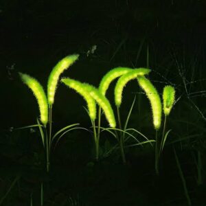 A cluster of glowing green, plant-like decorative light sticks illuminating a dark outdoor garden path at night.